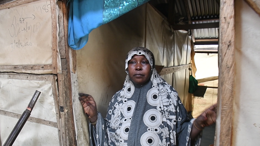 Hauwa stands by the door of her tent in Kawar Maila