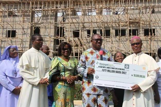 Former Anambra Governor, Peter Obi giving a cheque to one of the mission schools in the state with Prof. Stella Okunna and others watching